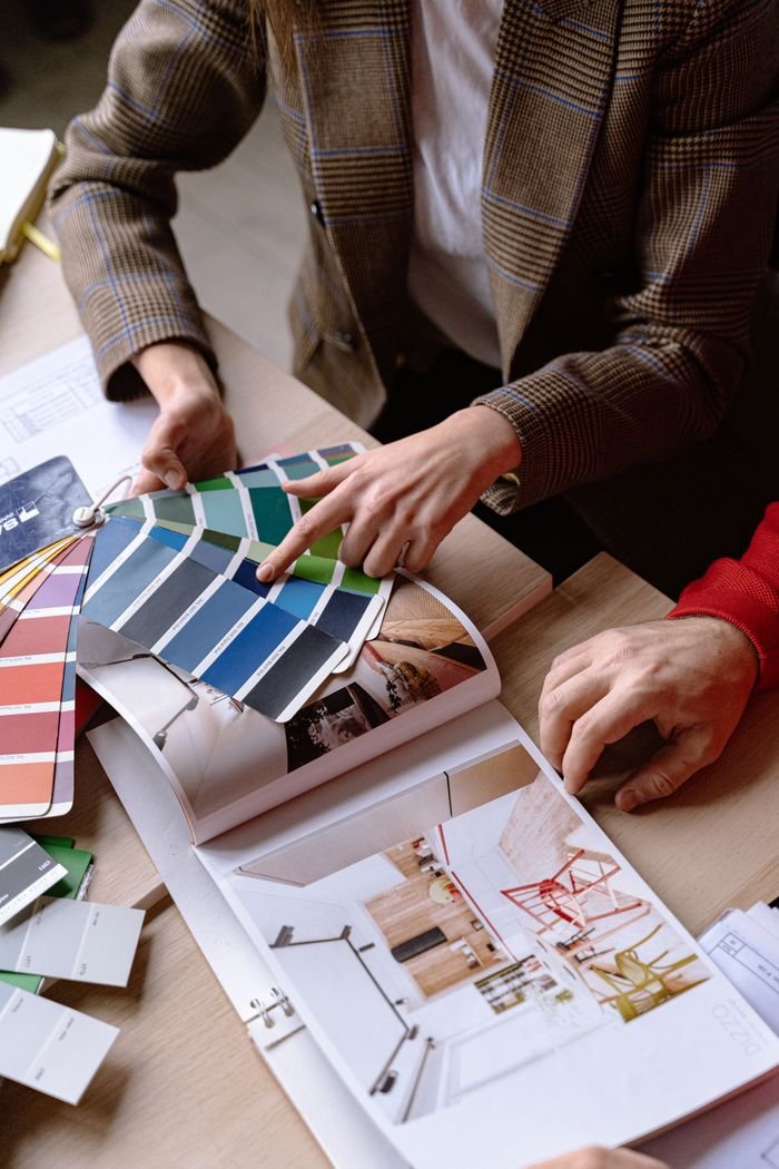 Features Interior designers discuss color swatches and design ideas at a table, planning a creative project.